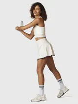 Falda skort deportiva de tiro alto, color blanco con borde inferior en contraste negro. Incluye short integrado con bolsillo lateral.