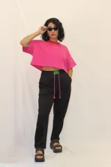 Pantalón de jogging negro de corte recto, con cintura elástica y cordones ajustables en color fucsia. Presenta un aplique decorativo de acrílico en la parte frontal de la cintura.