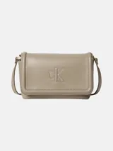 Cartera bandolera Calvin Klein de piel sintética suave en color beige, con solapa, cierre magnético, correa ajustable y monograma CK en relieve en la parte delantera.