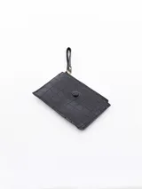 Billetera blanca con textura de cocodrilo, cierre de cremallera superior y un bolsillo frontal con solapa y botón a presión. Incluye una correa lateral para la muñeca.