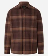 Camisa de manga larga con diseño de cuadros en tonos marrones, confeccionada en algodón. Presenta cuello camisero, cierre frontal con botones y un bolsillo en el pecho con botón.