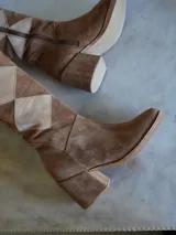 Bota alta de gamuza color marrón con diseño geométrico de rombos en tonos contrastantes, taco ancho y cómodo.