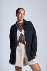 Sobrecamisa color beige de gabardina con cuello camisero, cierre frontal con botones a presión, dos bolsillos de parche en el pecho y corte holgado.