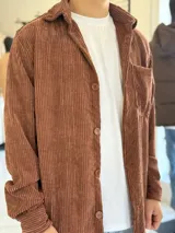 Sobrecamisa de pana color marrón chocolate, de manga larga, con cuello camisero, cierre frontal con botones y un bolsillo aplicado en el pecho.