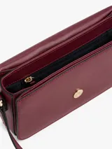 Cartera de hombro de cuero sintético color borgoña, con solapa frontal y cierre metálico con monograma TH. Posee correa ajustable y detalles metálicos dorados.