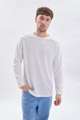 Remera manga larga de color blanco con cuello redondo a la base y mangas tipo raglán con textura acanalada.