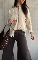 Sweater de punto color beige con bordado floral en el pecho, mangas largas y cuello redondo.