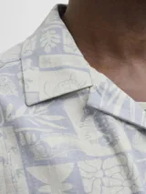 Camisa de manga corta con cuello resort y corte amplio. Presenta un estampado geométrico y botánico en tonos azul y crema. Confeccionada en una mezcla de viscosa y lino, ofrece un acabado liviano y fresco.
