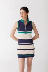 Vestido corto tejido de punto a rayas horizontales en tonos celeste, crema, marrón y mostaza. Tiene cuello alto y cierre metálico frontal. Sin mangas.