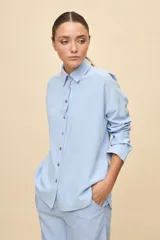 Camisa de calce relajado color celeste, con cuello clásico, botonadura frontal con botones en contraste y manga larga.