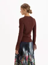 Top de tejido de punto fino color negro, con ajuste al cuerpo, cuello redondo y mangas largas que terminan en puños acampanados con detalle de tejido calado.