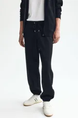 Pantalón deportivo de felpa de mezcla de algodón color negro, con cintura elástica ajustable mediante cordón, bolsillos en las costuras laterales y puños acanalados.