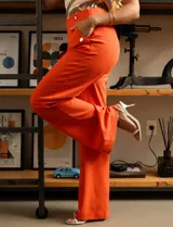 Pantalón naranja de crepe elastizado, corte recto, con bolsillos delanteros y apliques de botones metálicos.