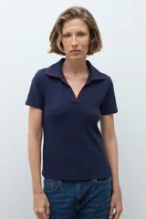Remera de punto tipo polo color azul marino, con cuello abierto y detalles de vivo en color rojo en el borde del cuello y las mangas.