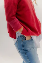 Buzo de punto en color negro con mangas tres cuartos y puños en contraste color marrón. Presenta un diseño holgado con tajos laterales y un aplique circular con logo en la parte inferior.