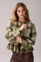 Blusa de tartán con diseño versátil, confeccionada en tela escocesa con detalles en cuero de oveja. Presenta cuello alto con forro de piel sintética, mangas largas con puños de cuero y piel, y un ruedo tableado con ajuste de cinturón de cuero en la cintura.