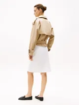 Gabardina beige de algodón con corte cropped, doble botonadura, cinturón y trabillas en los hombros.