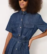 Vestido midi de jean azul, de manga corta, con bolsillos frontales con solapa, cierre frontal de botones y cinturón ajustable para anudar en la cintura.