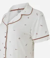 Pijama corto de dos piezas confeccionado en viscolycra blanca con estampado floral y vivo en contraste. Incluye una camisa de manga corta con cuello solapa y cierre frontal de botones, y un short con cintura elástica.