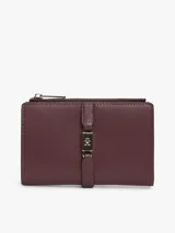 Billetera bifold Tommy Hilfiger de color bordó, confeccionada en poliuretano con acabado texturizado. Presenta un cierre principal con cremallera y un detalle frontal con logo metálico distintivo de la marca y broche.