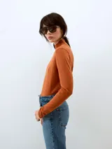 Sweater de punto color ladrillo, con cuello alto y mangas largas.