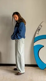 Jean wide leg de tiro alto y pierna ancha, confeccionado en denim de color celeste claro con acabado desgastado. Cuenta con diseño clásico de cinco bolsillos y cierre frontal con botón y cremallera.