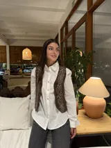 Chaleco marrón de corte corto con bordados florales en color crema en el frente y cierre frontal con botones. Presenta un diseño estructurado con cuello camisero.