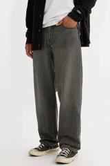 Jean de hombre color gris oscuro, de corte recto y holgado, con tiro bajo y cierre de bragueta. Cuenta con cinco bolsillos.