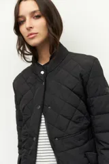 Campera capitoneada color beige, de cuello alto, con bolsillos de solapa y botones metálicos.