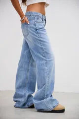Pantalón de denim tiro bajo, color gris lavado, de corte recto y holgado. Presenta una línea de tachas metálicas pequeñas a lo largo de la costura lateral externa.