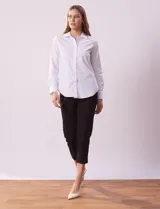 Camisa blanca de algodón con cuello con solapa, abertura central con botones y mangas largas con puño y botón.