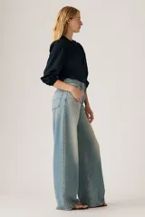 Jeans de corte recto y tiro alto, con diseño de pierna ancha y acabado lavado en tono celeste claro. Presentan cierre frontal con botón y cremallera, además de bolsillos laterales y traseros.