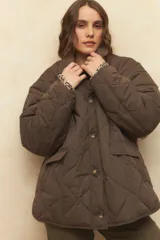 Campera capitoneada negra con botones veteados, bolsillos laterales de solapa y forro de satén con estampado animal print.