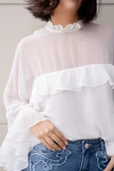 Blusa blanca de gasa con volados en el frente y mangas acampanadas.