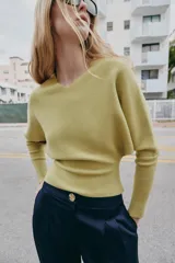 Jersey de punto color verde lima, con cuello pico y manga larga de sisa ancha que se estrecha hacia la muñeca.
