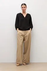 Blusa negra de manga larga con diseño de tejido plumeti y escote en V.