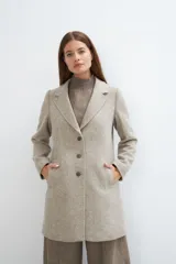 Saco corto entallado de lana fina, con cuello solapa, manga larga y cierre frontal con botones. Presenta un diseño clásico con textura de espiga en tonos tierra.