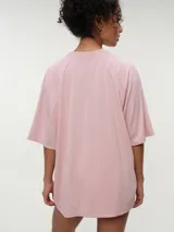 Remera deportiva de color rosado con diseño oversized y mangas raglán cortas, confeccionada en tela dry fit. Cuenta con cuello redondo clásico y detalle de etiqueta en el lateral inferior.