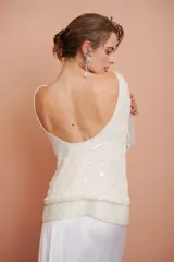 Blusa blanca con bordado de mostacillas y lentejuelas, escote redondo y manga larga.