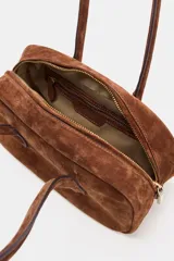 Bolso de hombro de formato alargado confeccionado en gamuza color marrón. Cuenta con doble asa de hombro y cierre superior mediante cremallera metálica.