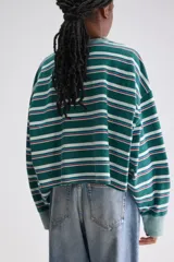 Remera cropped de manga larga y silueta oversize de algodón, con cuello redondo y diseño a rayas horizontales en tonos verdes, blancos y rojos. Cuenta con un pequeño bordado en el pecho.