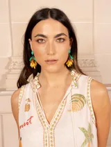 Vestido largo color crema con estampado de flores y corazones en tonos azules, naranjas y amarillos. Tiene cuello en V con ribete azul y corte imperio con falda escalonada.