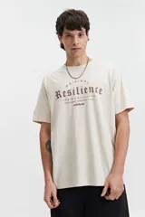 Remera de manga corta color beige, con escote redondo y fit regular. Presenta un estampado frontal en color marrón con la palabra "Resilience" en tipografía gótica y el texto "Original The World Has Changed Established Since 1976 // NLD Mistral".