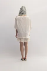 Remerón gris de cuello bote, con bordado del monograma de la marca a tono y encaje blanco integrado en el ruedo. Confeccionado en malla fina compactada de algodón.