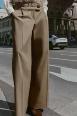 Pantalón de tiro medio con pernera ancha, confeccionado con pinzas delanteras y bolsillos laterales. Presenta un cierre frontal con cremallera y un botón decorativo dorado con relieve.