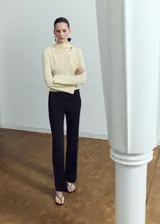 Blusa de manga larga color amarillo claro, con cuello alzado y detalle de abertura asimétrica en el escote.