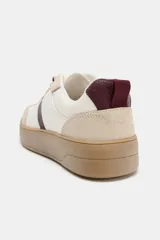 Zapatilla tipo bamba con diseño de paneles en combinación de colores y materiales, incluyendo detalles en cuero sintético y gamuza. Presenta suela de plataforma en contraste y cierre mediante cordones.