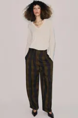 Pantalón de tiro alto con diseño fluido y estampado de cuadros en tonos oscuros. Presenta pliegues frontales, bolsillos delanteros con solapa y cierre frontal con cremallera, botón y ganchos metálicos.