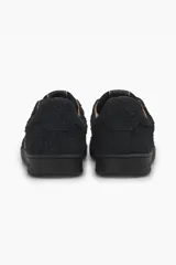 Zapatillas bajas de cuero negro con perforaciones y suela de goma.