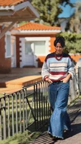 Sweater de punto con diseño de franjas horizontales en tonos rosa, celeste, blanco y marrón. Presenta cuello redondo y mangas largas con corte relajado.